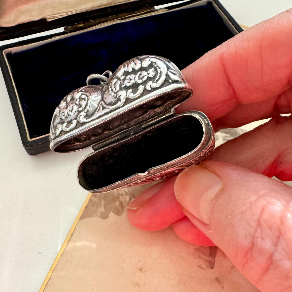 Silver decorative box with intricate patterns held by a hand