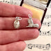 Two silver charms on a hand with sheet music in the background