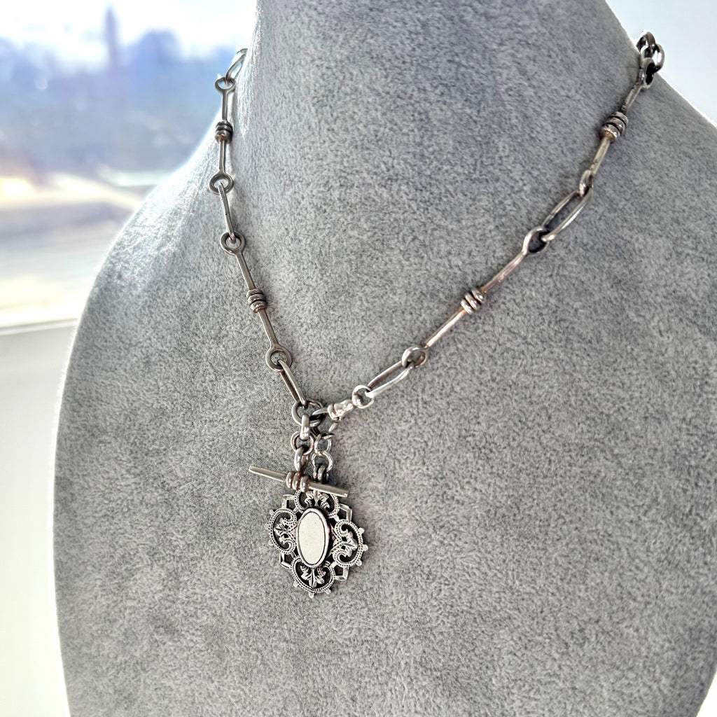 Silver necklace with a pendant on a mannequin bust.