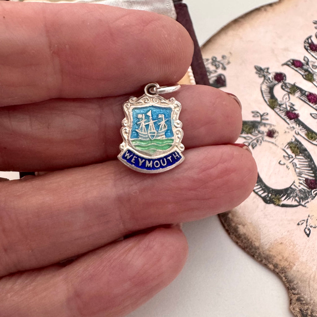 Small silver and enamel 'Weymouth' pendant held between fingers