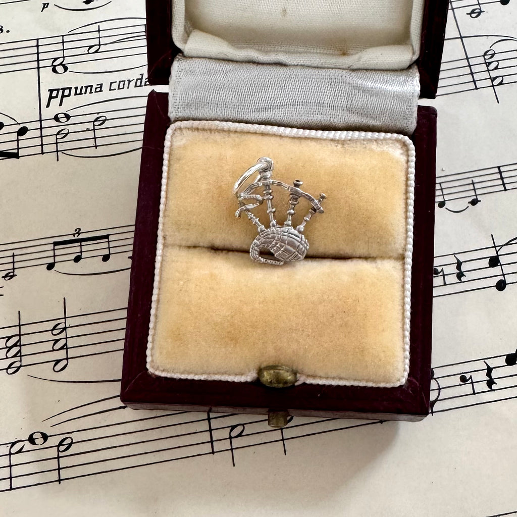 Silver bagpipe charm in a jewelry box on sheet music