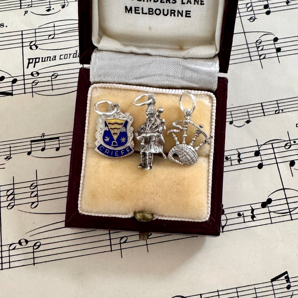 Three vintage silver Scottish themed charms in a jewelry box on sheet music