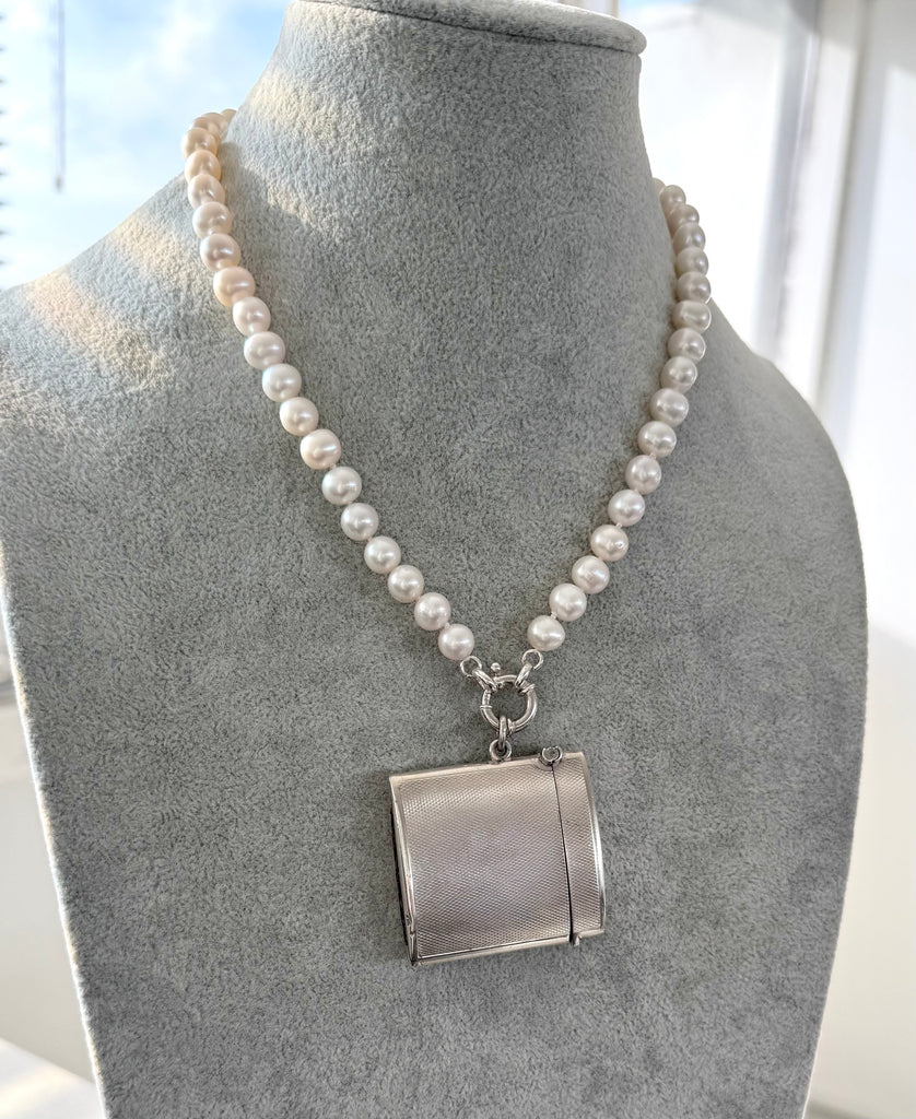 Vintage 1935 hallmarked vesta case made by G&SC Ltd of Regent St, London on a pearl necklace on a grey mannequin