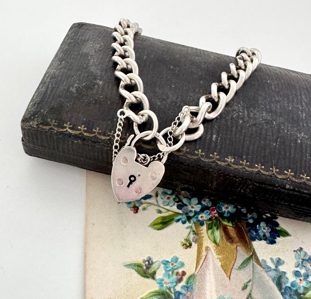Vintage 1963 sterling silver heart padlock bracelet on a vintage jewellery box and with a vintage postcard