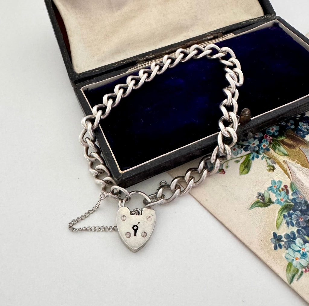 Vintage 1963 sterling silver heart padlock bracelet on a vintage jewellery box and with a vintage postcard