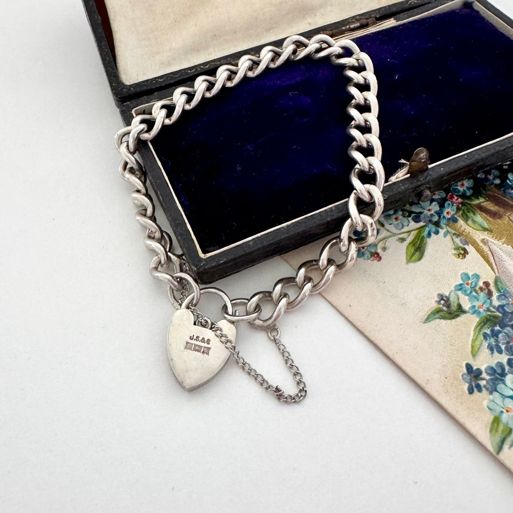 Vintage 1963 sterling silver heart padlock bracelet on a vintage jewellery box and with a vintage postcard