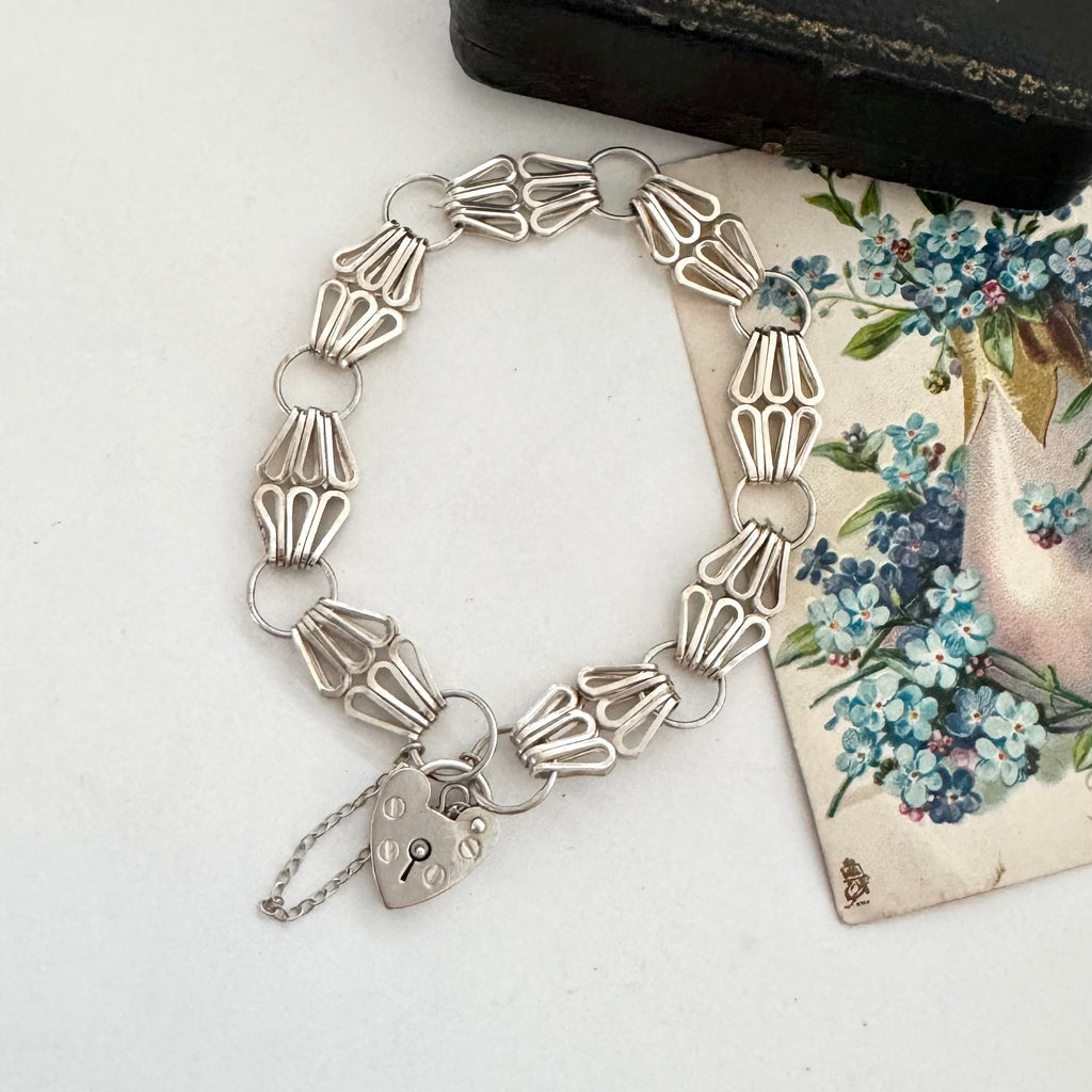 Silver bracelet with a lock charm on a floral card