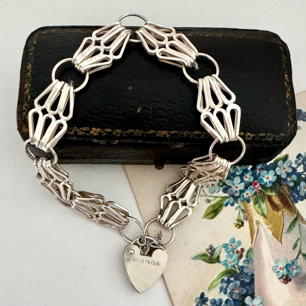 Silver bracelet with heart charm on a floral-patterned fabric background