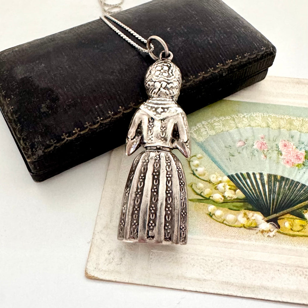 Vintage figural sterling silver needle cae necklace on an old jewellery box and with a vintage postcard