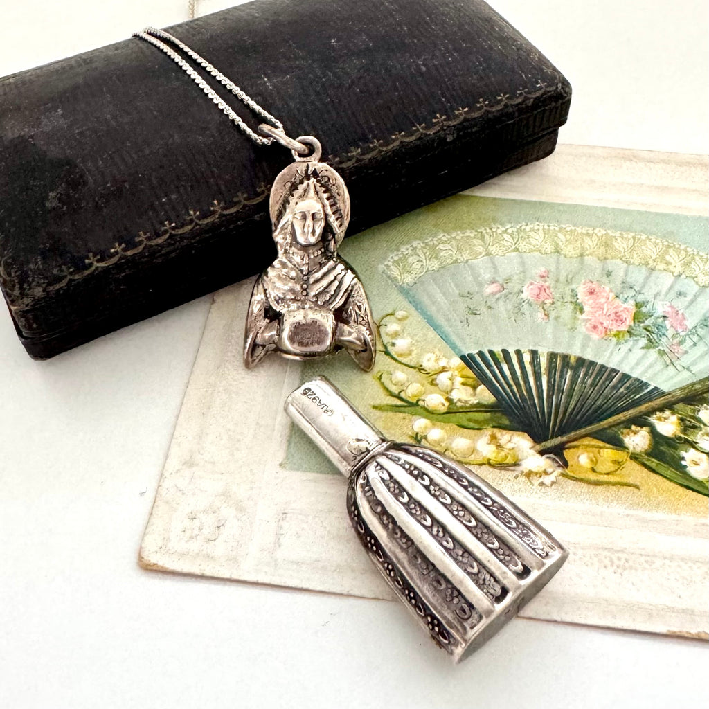 Vintage figural sterling silver needle cae necklace on an old jewellery box and with a vintage postcard