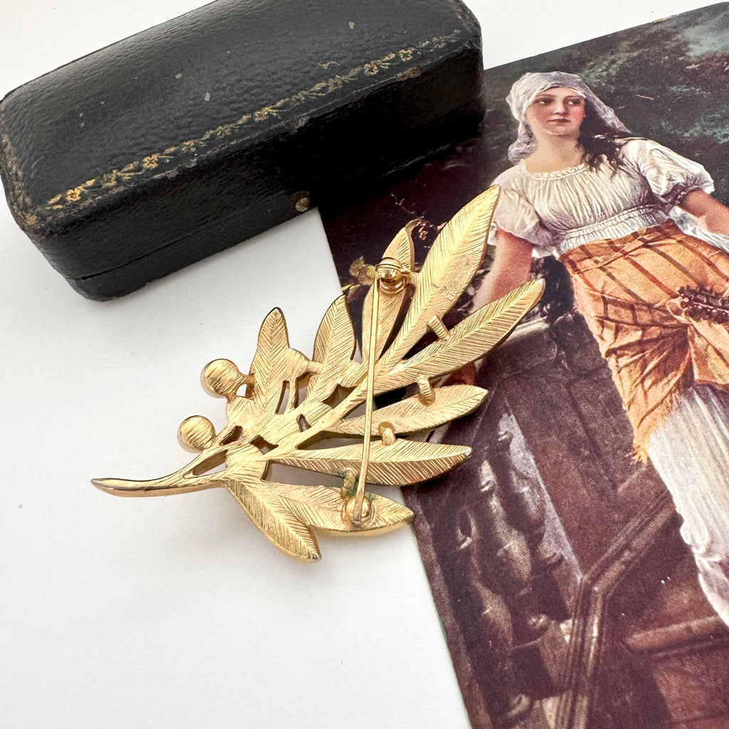 Gold leaf vintage Trifari brooch with a vintage illustration of a woman in a dress.