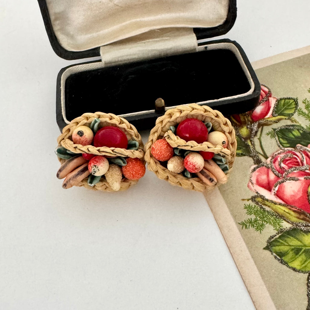 Vintage basket of fruit earrings in a black jewelry box on a white surface.