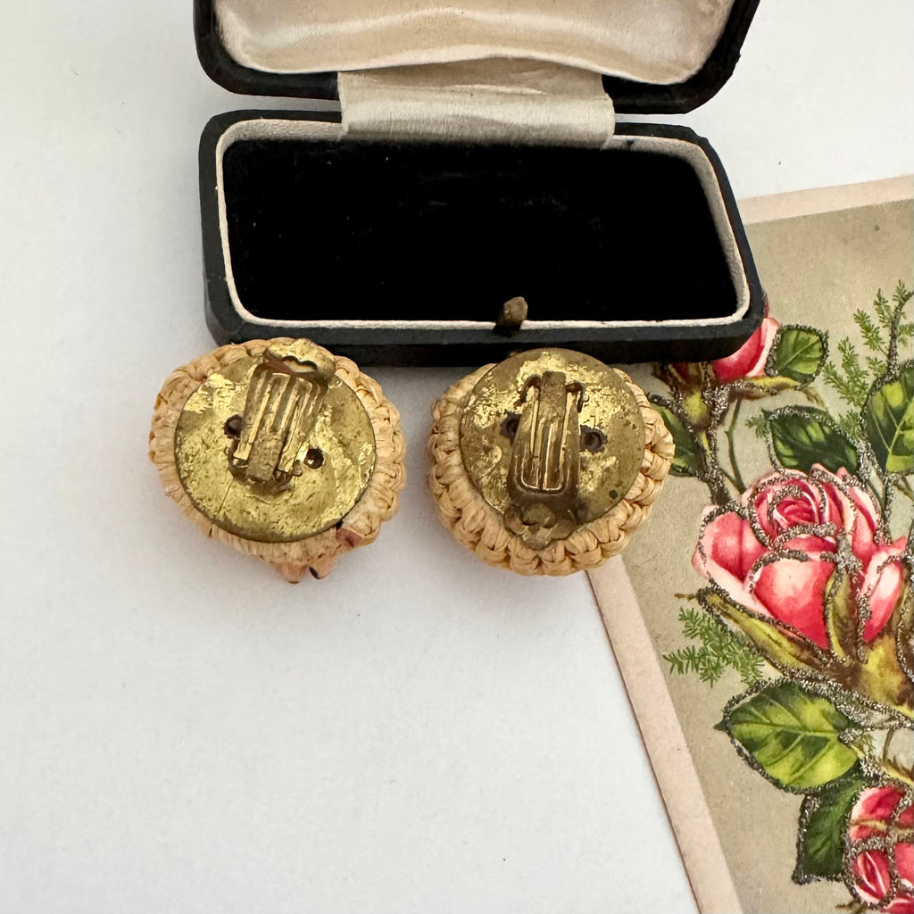 Back of vintage clip on earrings on a white surface next to an open jewelry box.