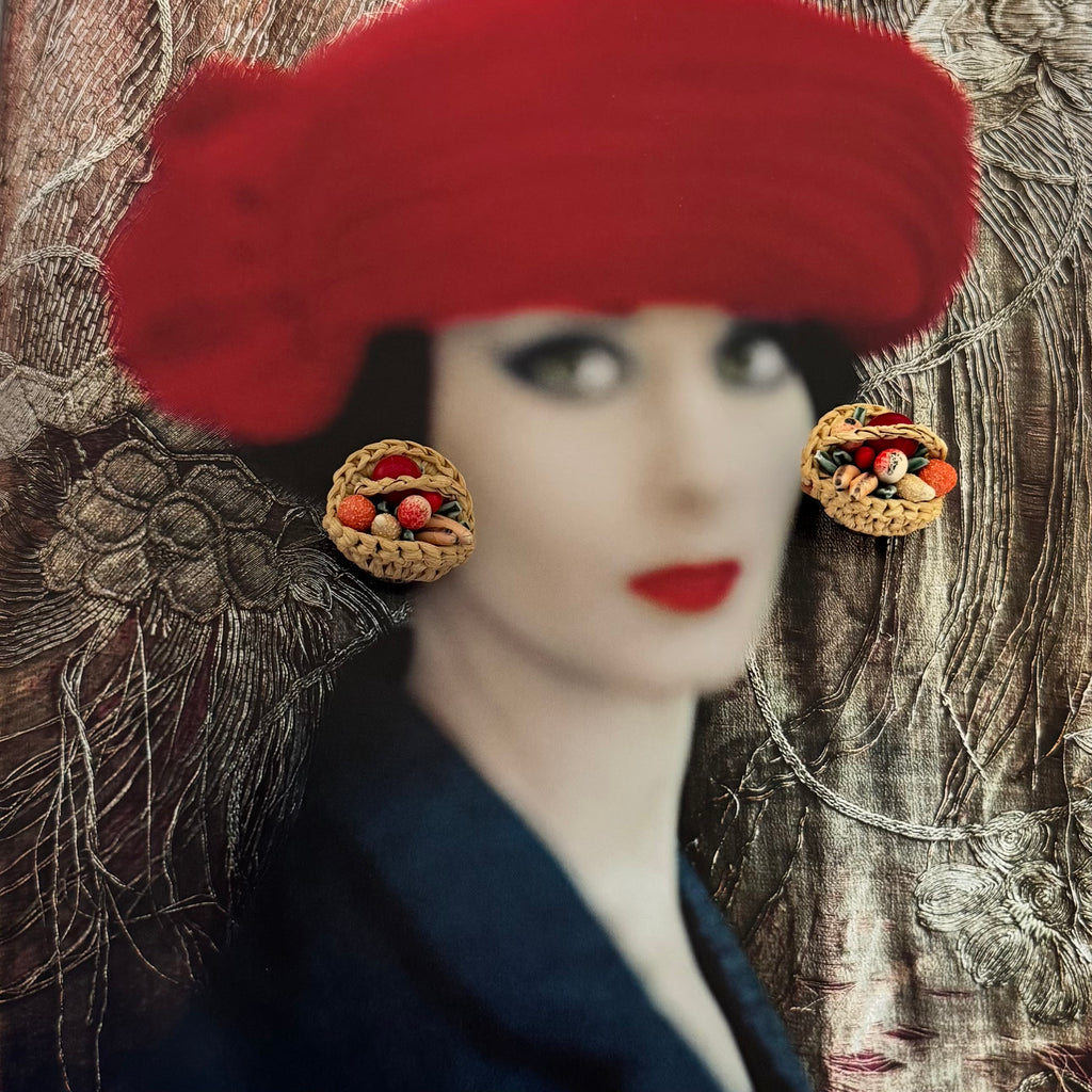 Artistic depiction of a woman wearing a red hat and decorative earrings against a textured background.