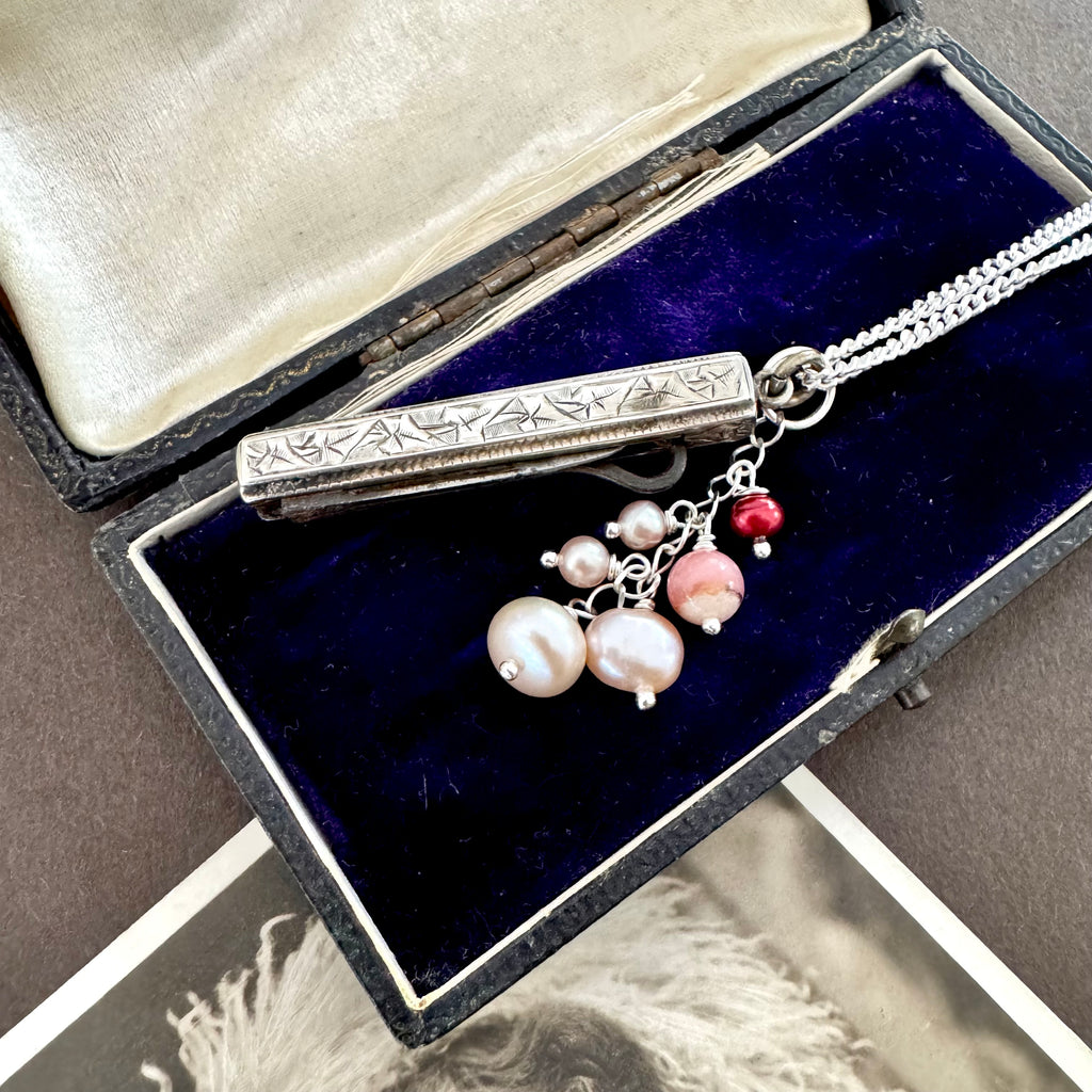 Vonk Jewellery antique 1885 button hook and pearl charm necklace on a brown background and with a vintage postcard and jewellery box