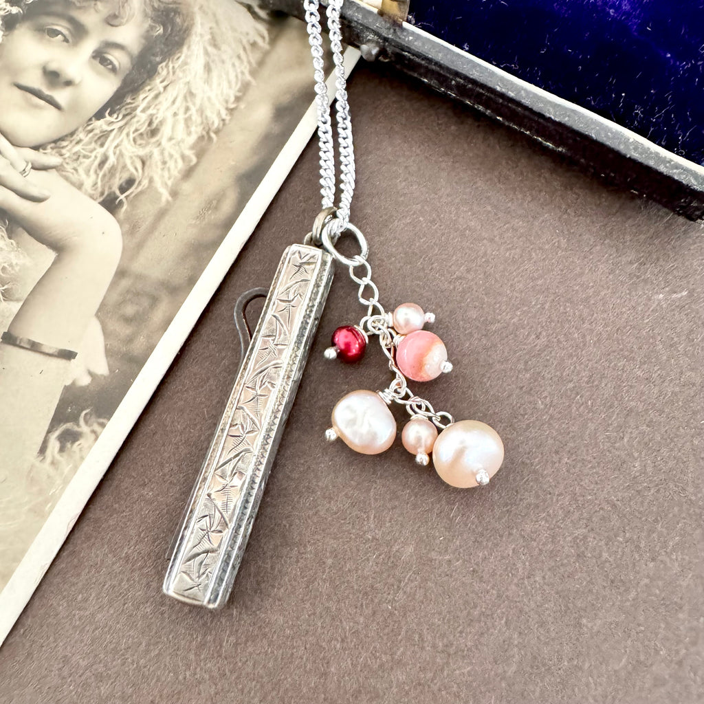 Vonk Jewellery antique 1885 button hook and pearl charm necklace on a brown background and with a vintage postcard and jewellery box