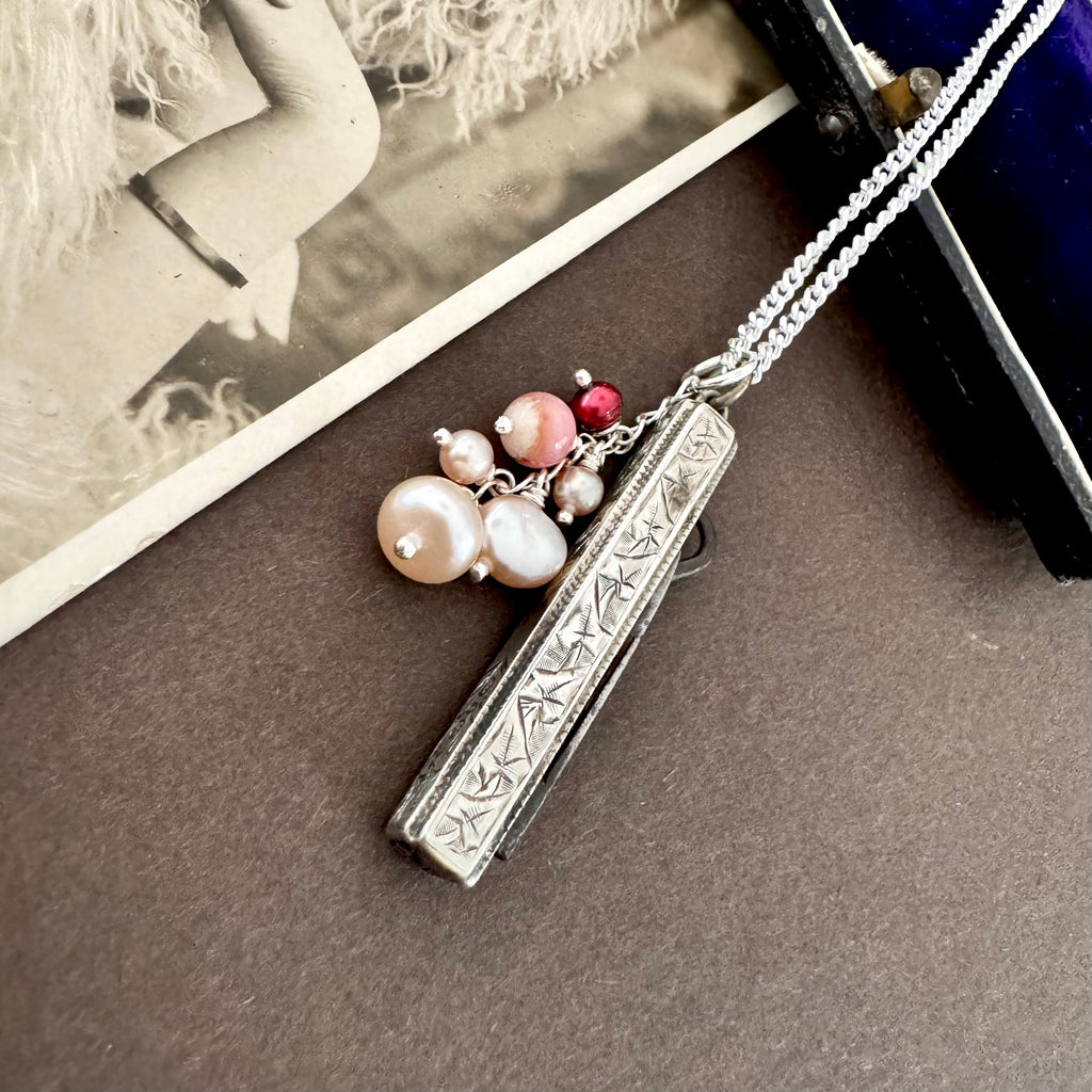 Vonk Jewellery antique 1885 button hook and pearl charm necklace on a brown background and with a vintage postcard and jewellery box