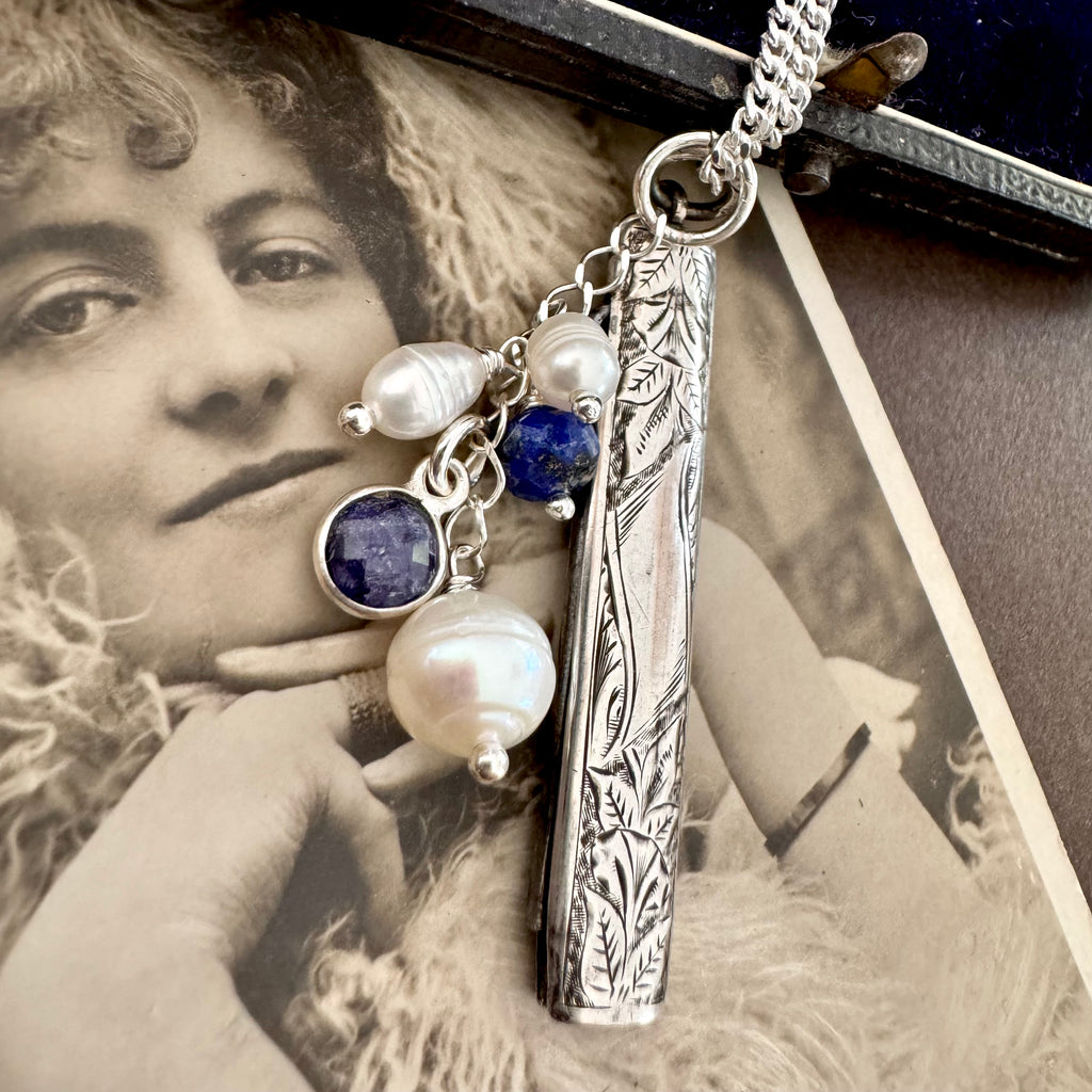 Vonk Jewellery 1894 silver button hook and pearl and lapis charm necklace on a vintage postcard and vintage jewellery box