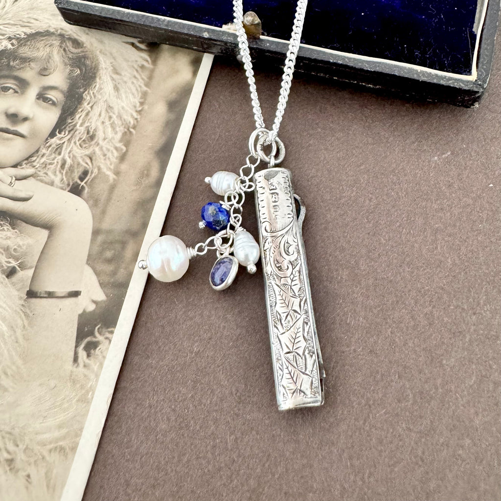 Vonk Jewellery 1894 silver button hook and pearl and lapis charm necklace on a vintage postcard and vintage jewellery box
