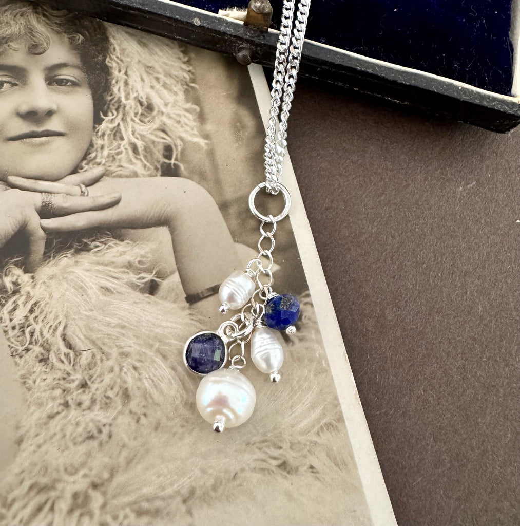 Vonk Jewellery 1894 silver button hook and pearl and lapis charm necklace on a vintage postcard and vintage jewellery box