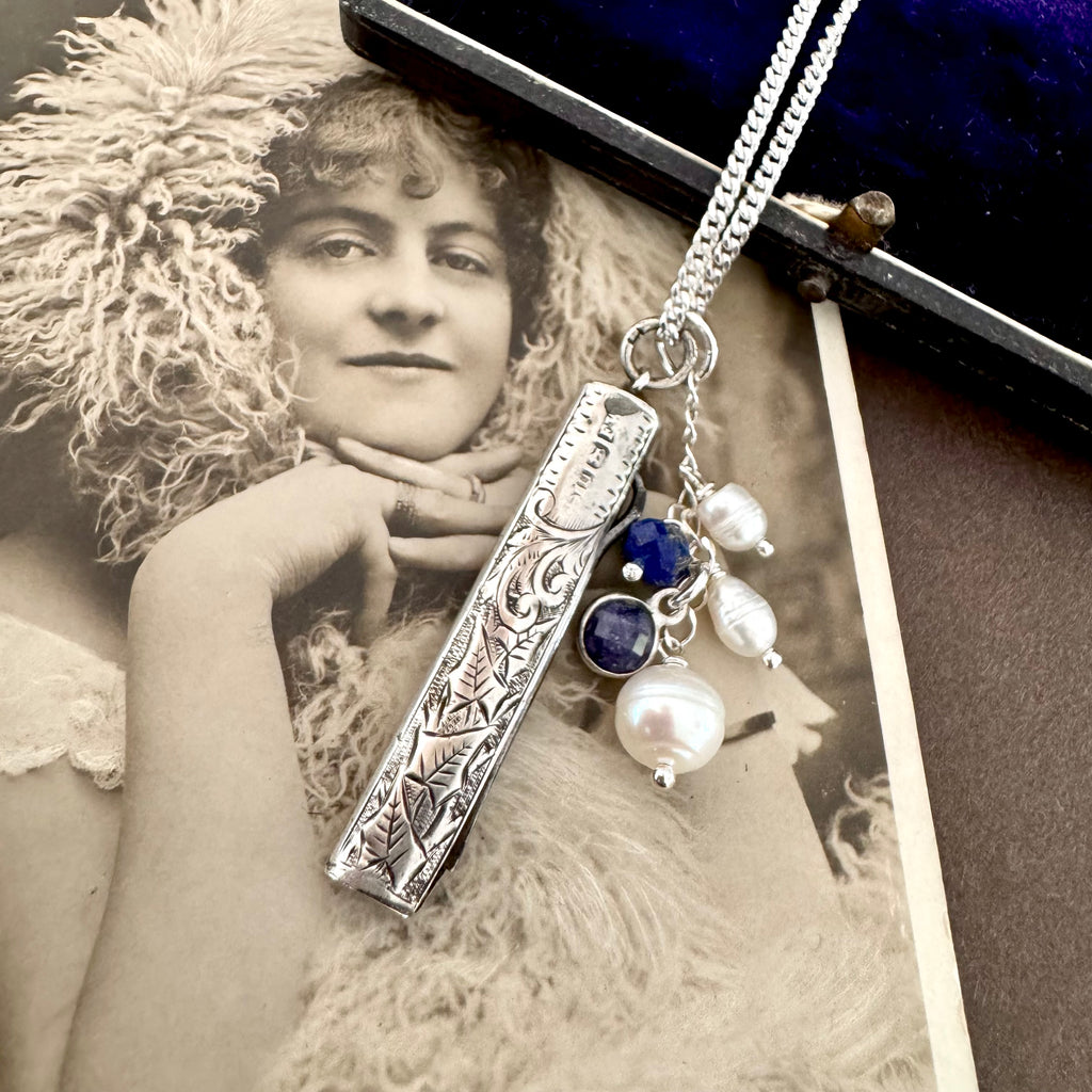 Vonk Jewellery 1894 silver button hook and pearl and lapis charm necklace on a vintage postcard and vintage jewellery box
