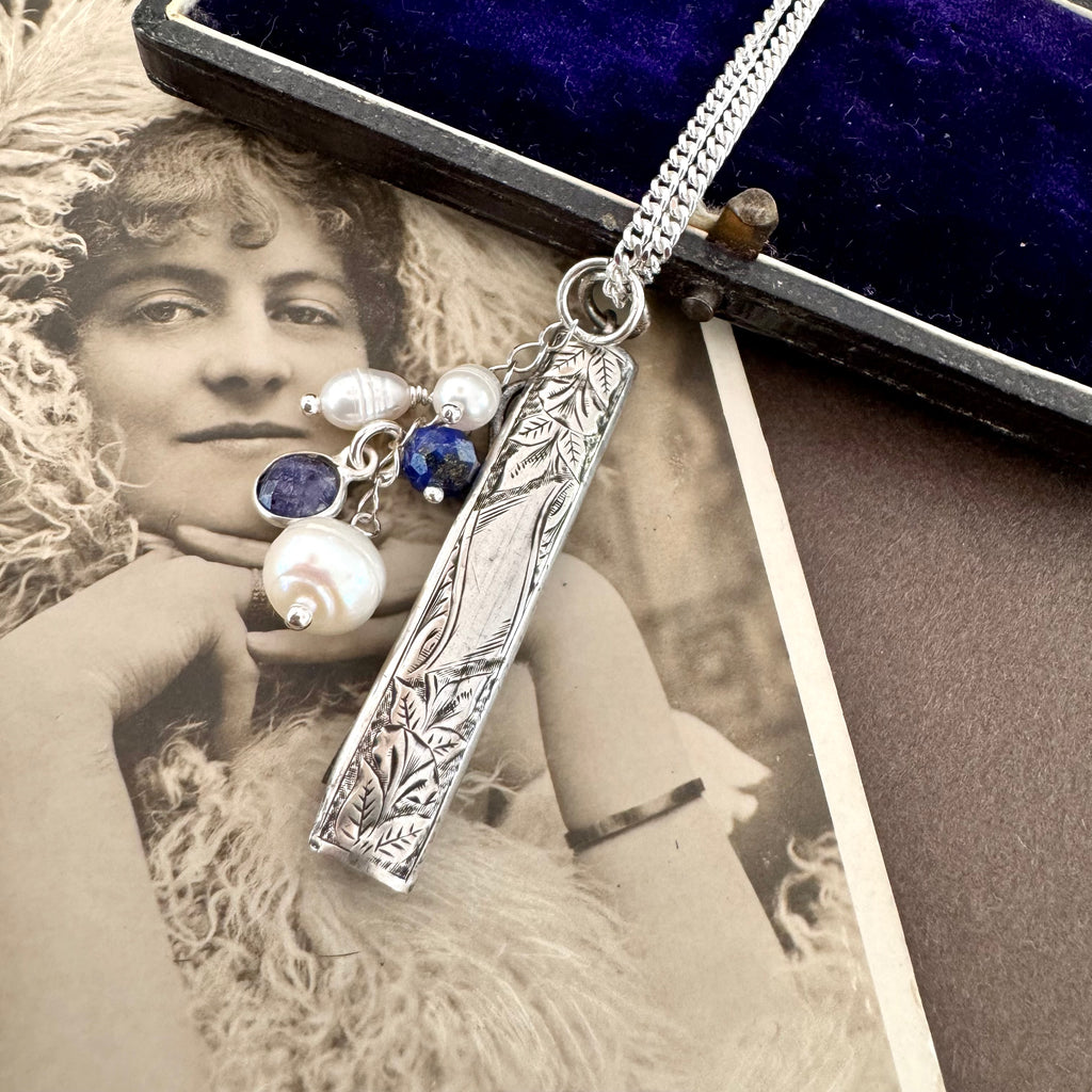 Vonk Jewellery 1894 silver button hook and pearl and lapis charm necklace on a vintage postcard and vintage jewellery box