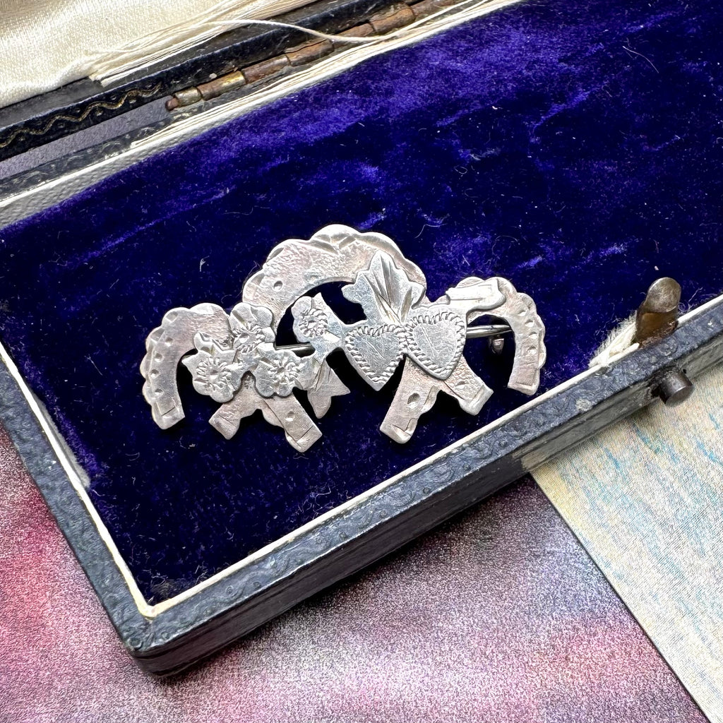 Vonk Jewellery sterling silver sweetheart brooch featuring horseshoes, hearts and flowers on a vintage jewellery box