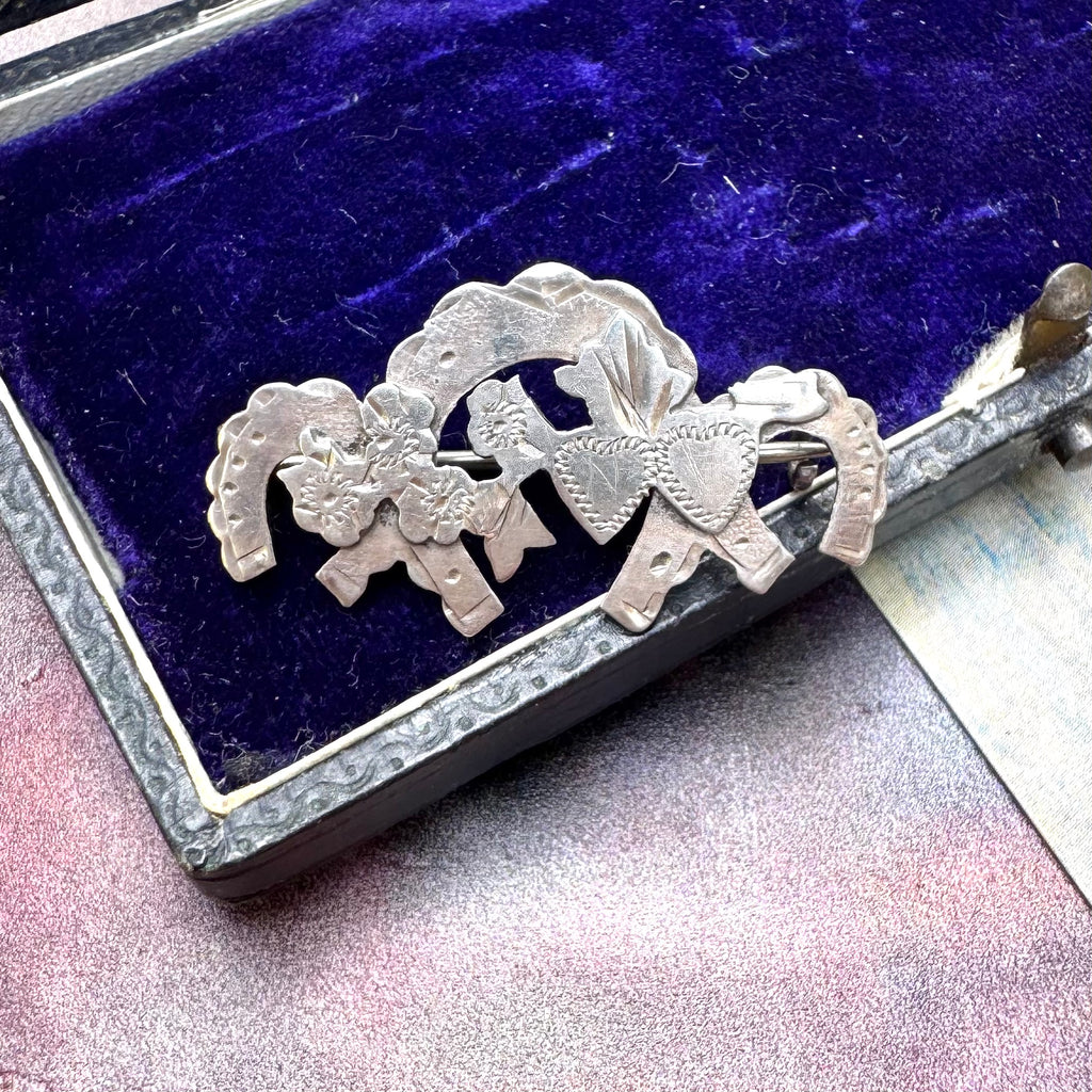 Vonk Jewellery sterling silver sweetheart brooch featuring horseshoes, hearts and flowers on a vintage jewellery box