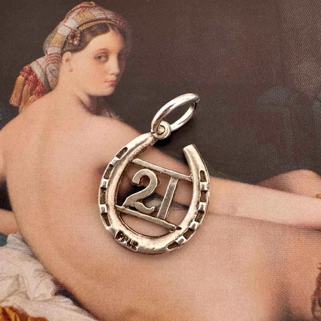 Vonk Jewellery 1963 hallmarked lucky horseshoe charm on an Ingres painting of a woman