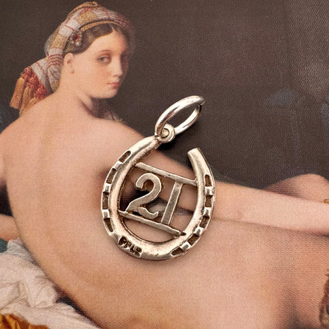 Vonk Jewellery 1963 hallmarked lucky horseshoe charm on an Ingres painting of a woman