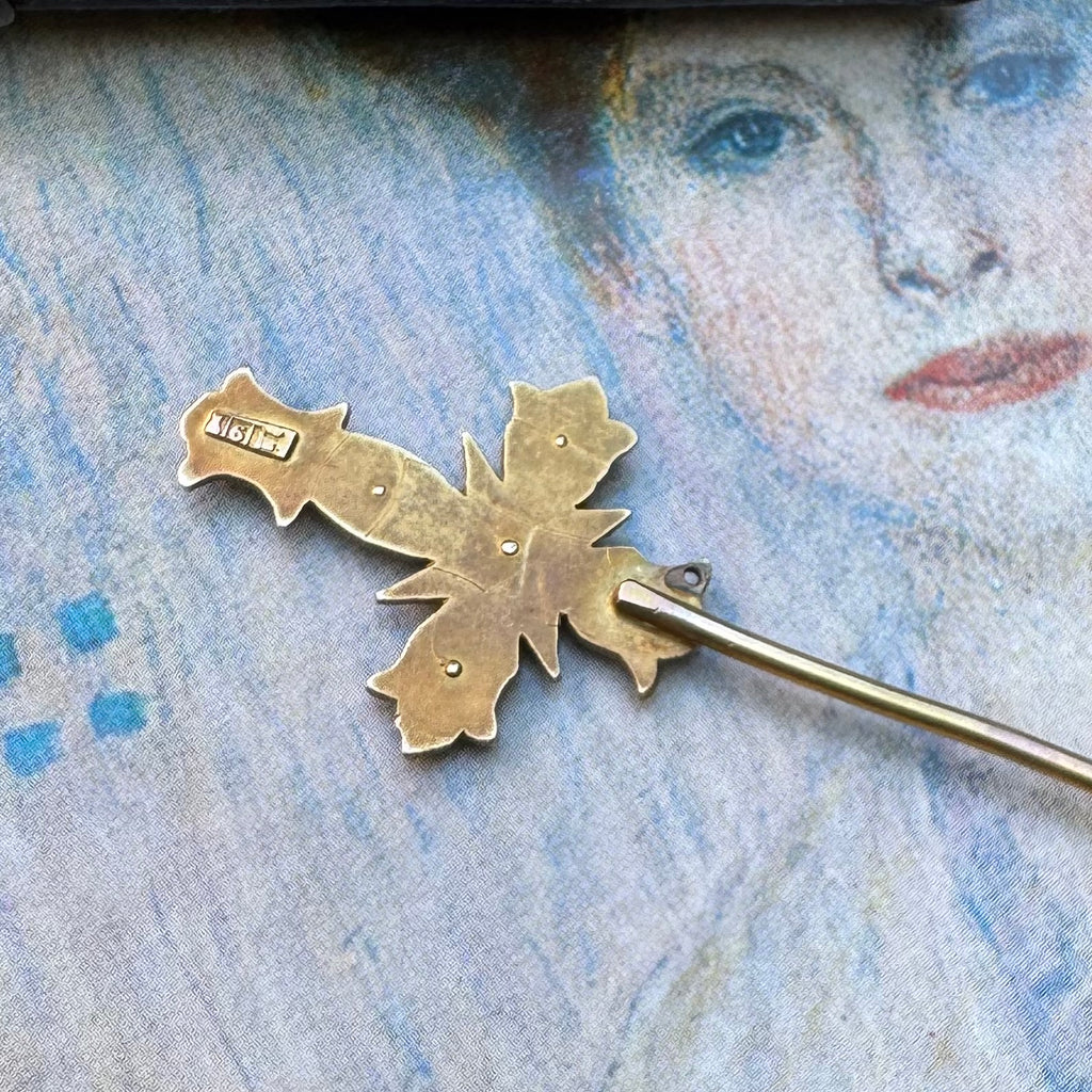 Back of Vonk Jewellery Aronsons 9ct gold and pearl crucifix stick pin on a vintage postcard