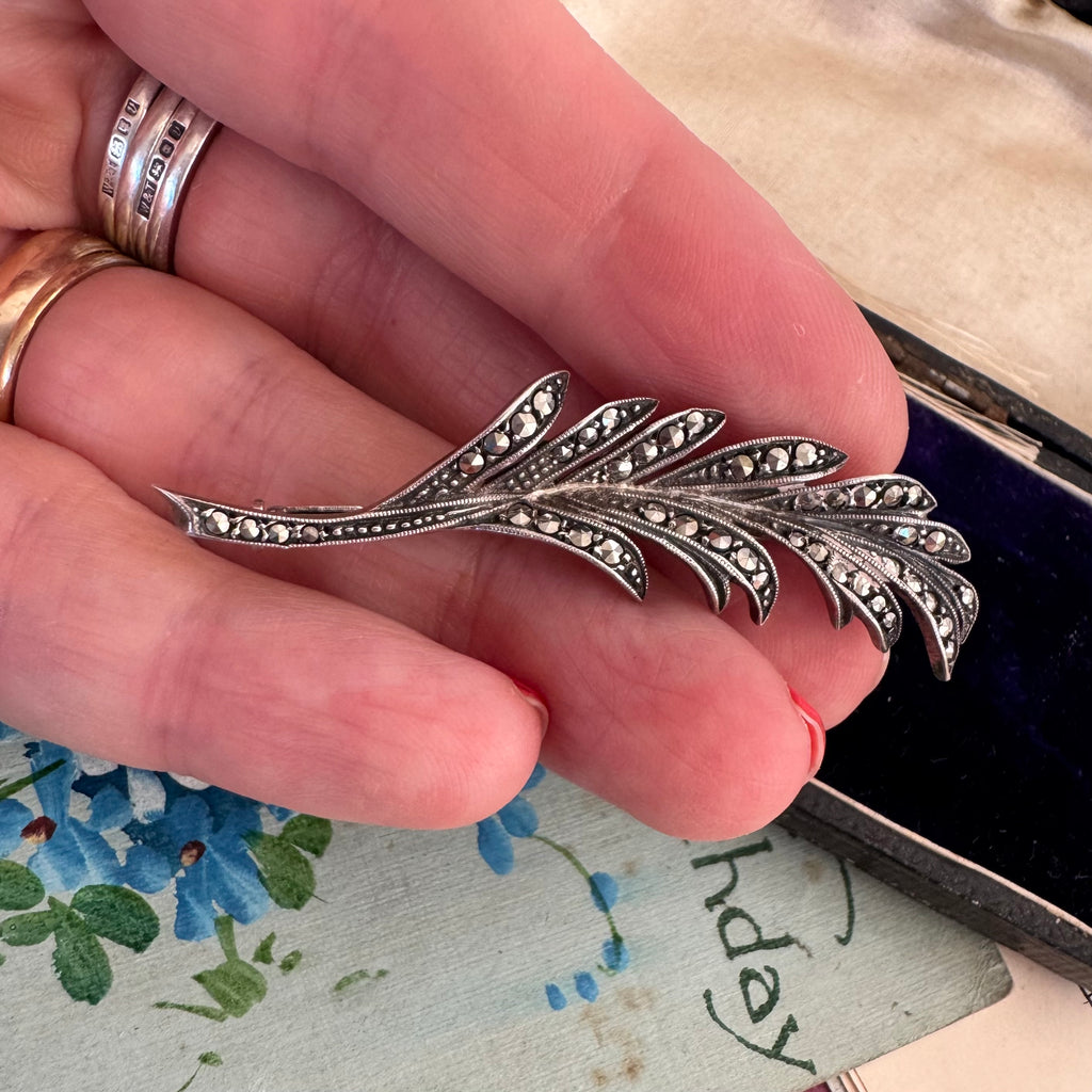 Vonk Jewellery French marcasite leaf brooch with trombone clasp on a vintage postcard and with a vintage jewellery box and in a woman's hand