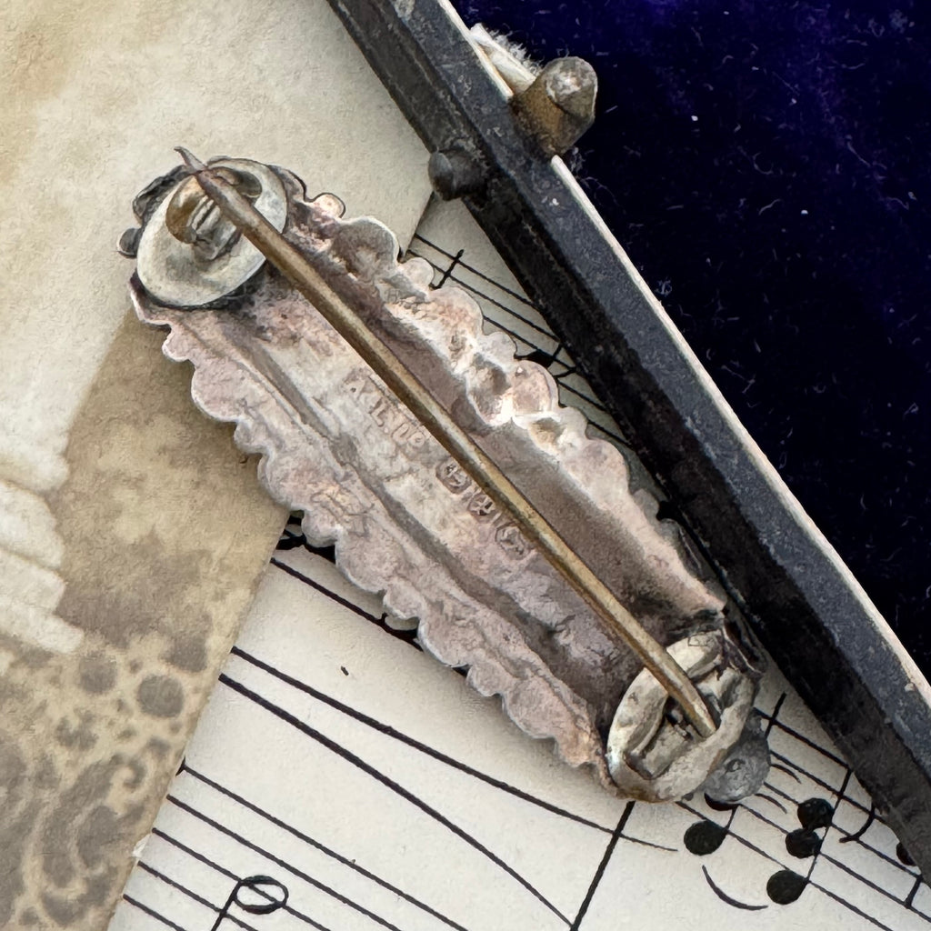 Back of Vonk Jewellery Victorian 1889 silver brooch on a vintage postcard and with vintage sheet music