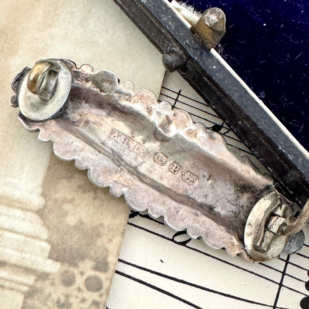 Back of Vonk Jewellery Victorian 1889 silver brooch on a vintage postcard and with vintage sheet music