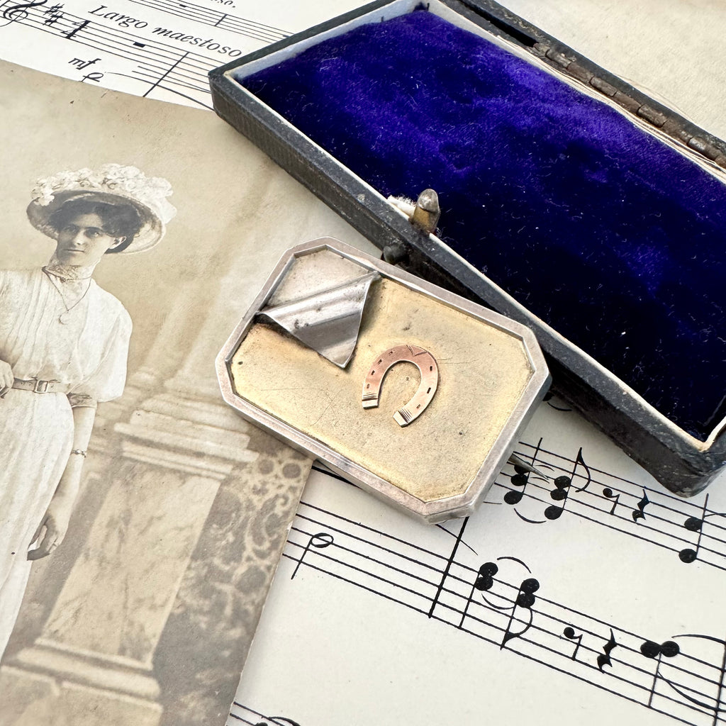 Vonk Jewellery antique silver horseshoe locket brooch on a vintage postcard, vintage sheet music and a vintage jewellery box