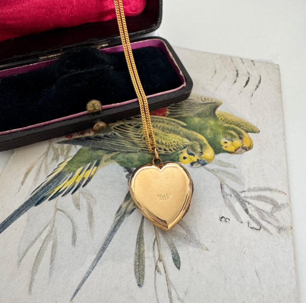 Vonk Jewellery rolled gold vintage heart locket on a vintage jewellery box and vintage postcard of love birds.