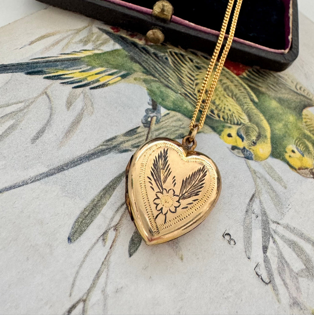 Vonk Jewellery rolled gold vintage heart locket on a vintage jewellery box and vintage postcard of love birds.