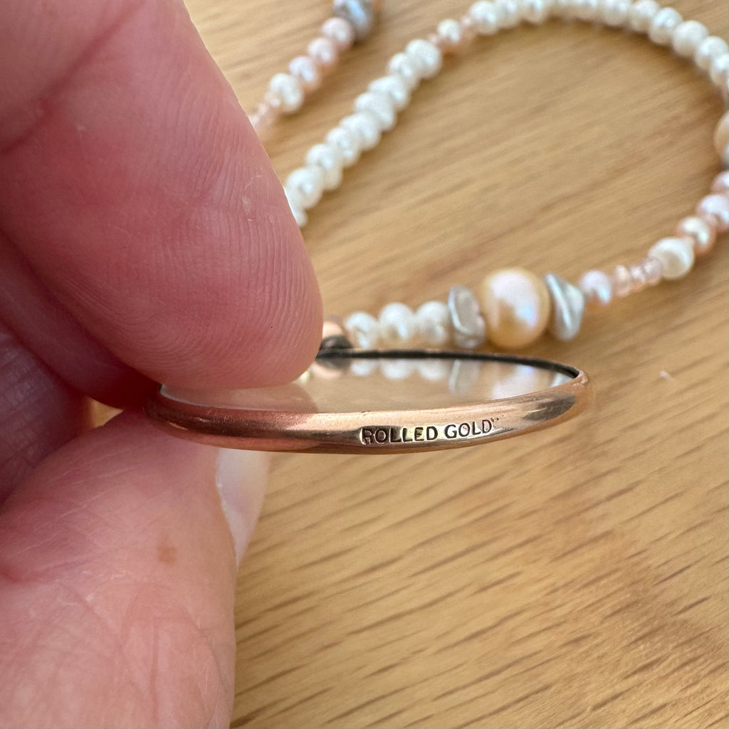 Vonk Jewellery rolled gold locket in a womans fingers to show the stamp