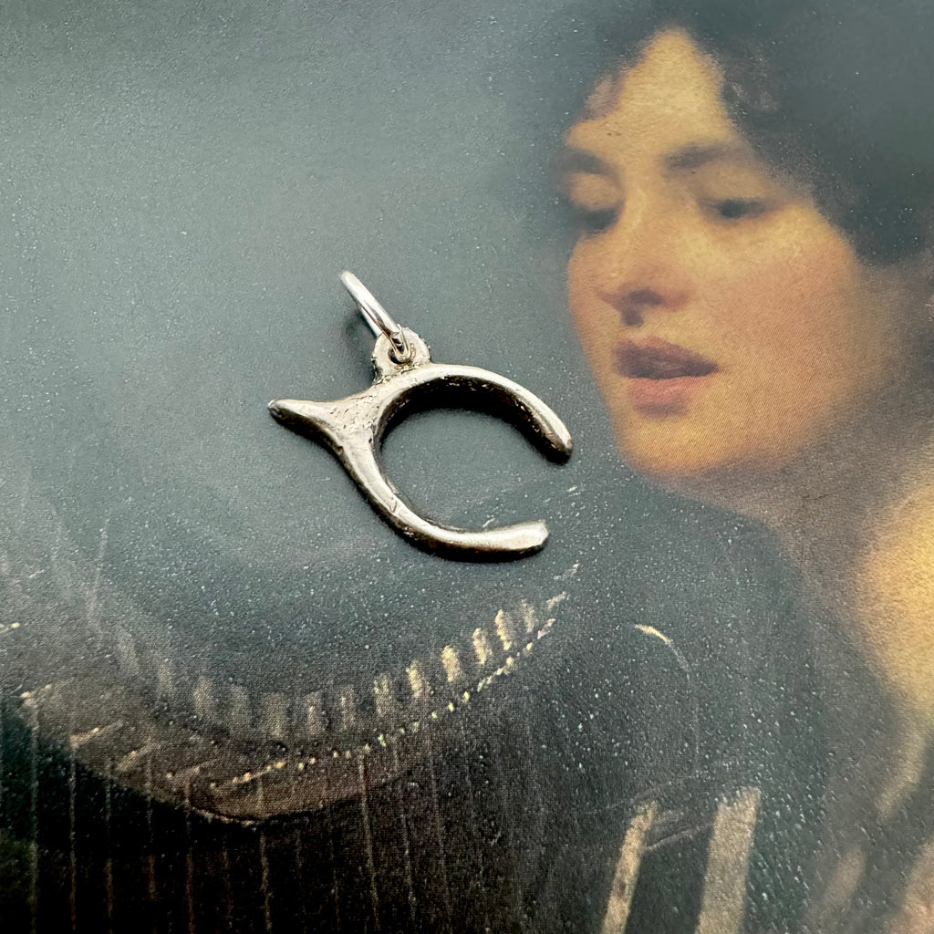 Vonk Jewellery silver vintage lucky wishbone charm on a picture of a woman playing a harp