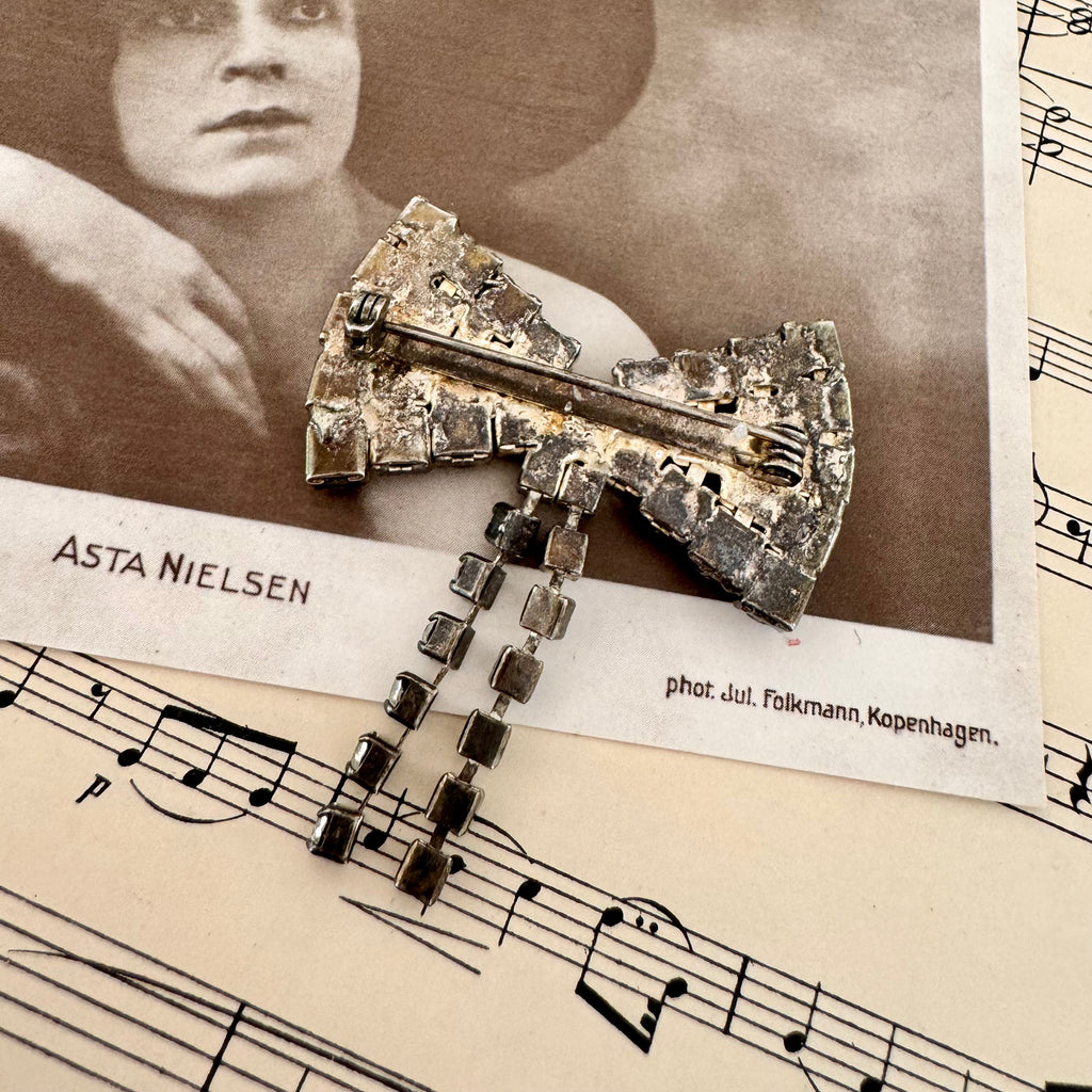 Back of Vonk Jewellery vintage 1950's rhinestone bow brooch on a vintage postcard and vintage sheet music