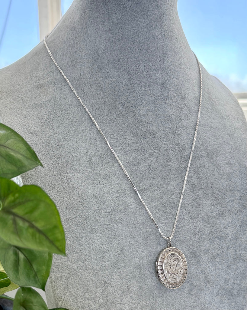 Vonk Jewellery 1977 sterling silver engraved locket on a grey jewellery display neck