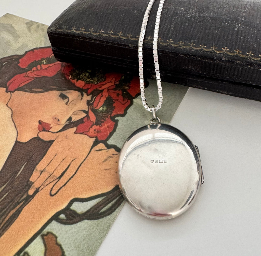 Vonk Jewellery 1977 sterling silver engraved locket on a vintage jewellery box and with a card of a woman with red flowers in her hair