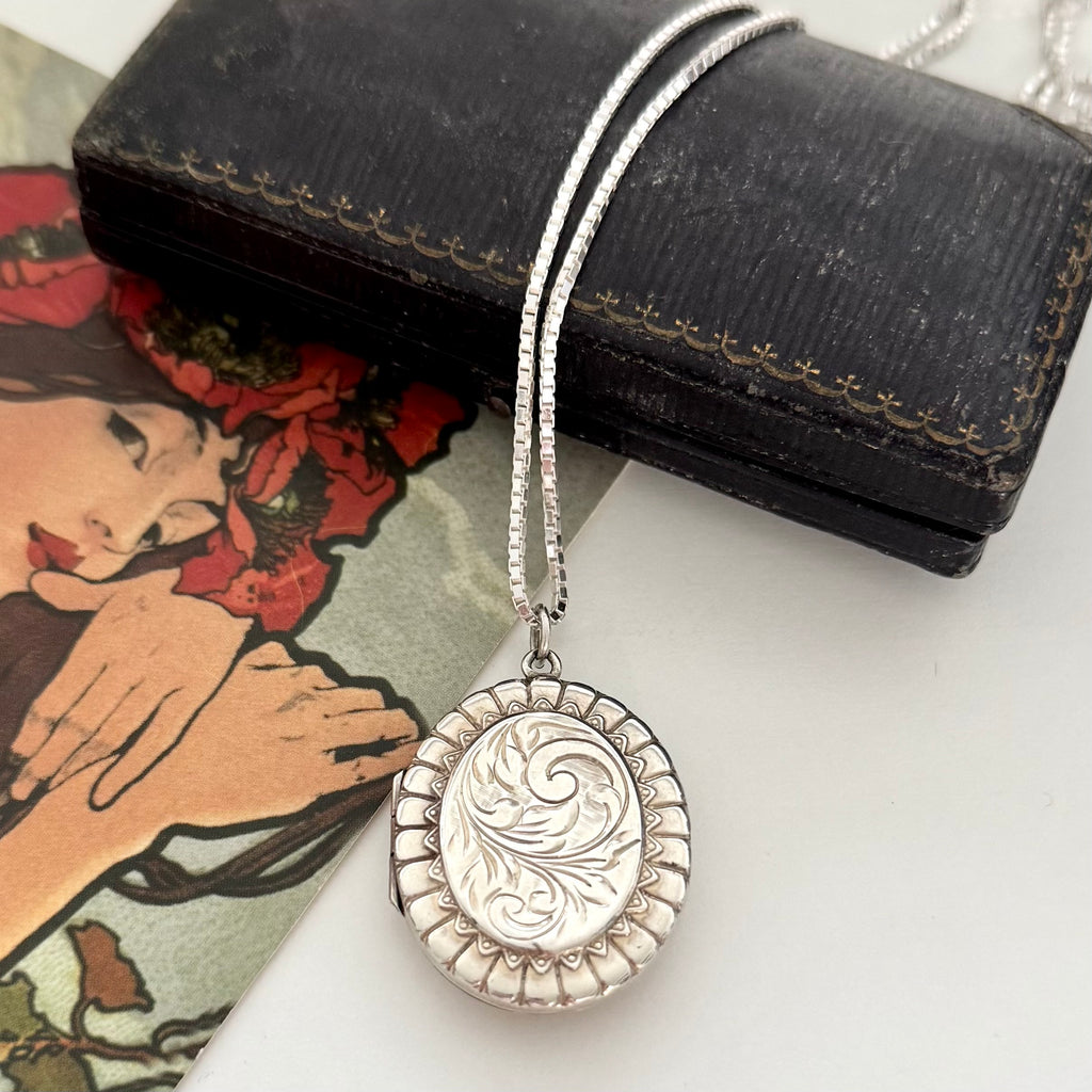 Vonk Jewellery 1977 sterling silver engraved locket on a vintage jewellery box and with a card of a woman with red flowers in her hair