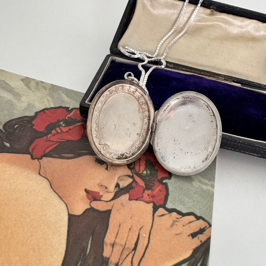 Vonk Jewellery 1977 sterling silver engraved locket on a vintage jewellery box and with a card of a woman with red flowers in her hair