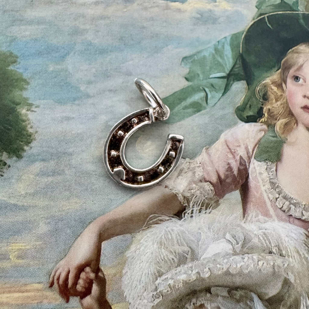 Vonk Jewellery vintage silver horseshoe charm on a picture of an old painting