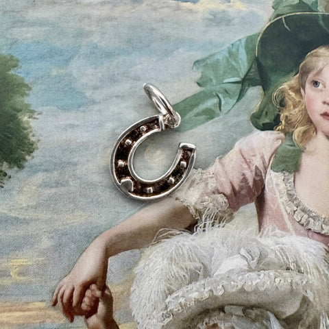 Vonk Jewellery vintage silver horseshoe charm on a picture of an old painting