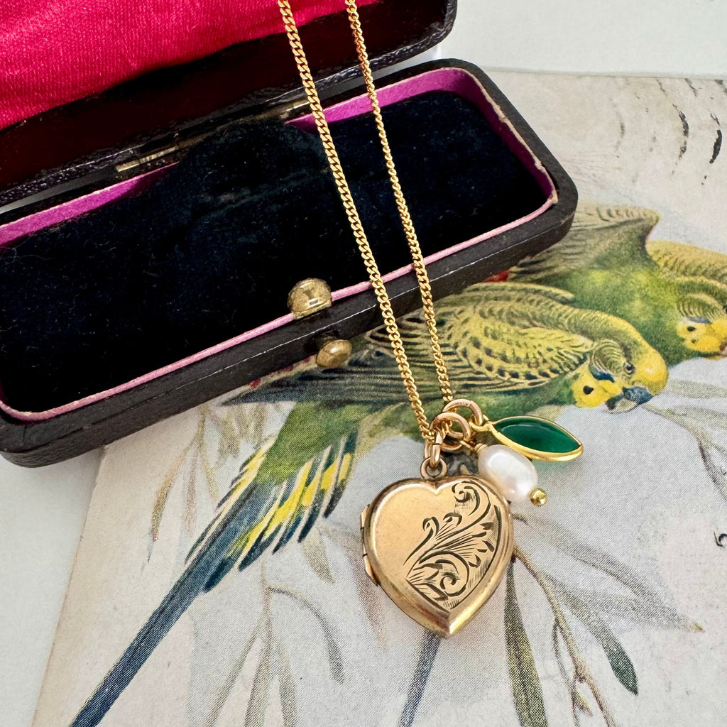 Vonk Jewellery rolled gold pearl and green onyx charm necklace on a vintage jewellery box and with a vintage postcard of love birds