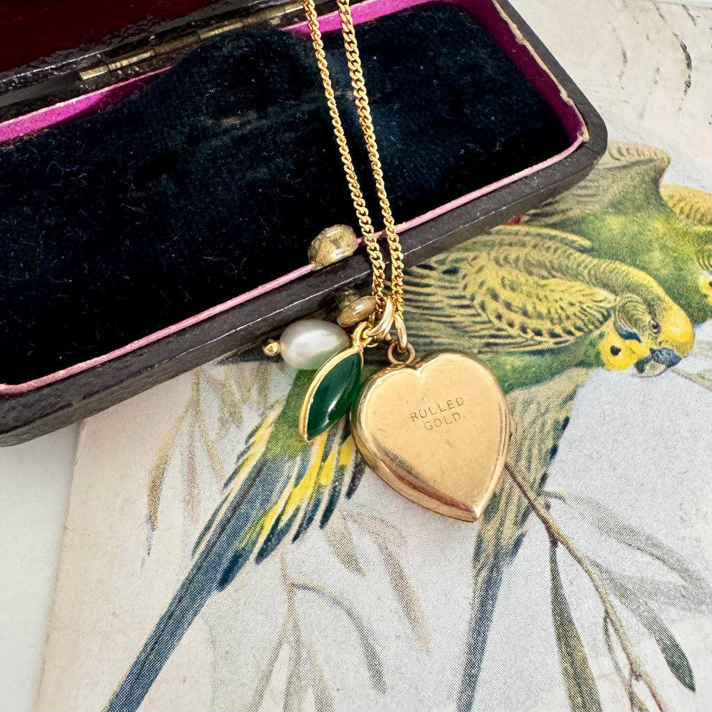 Vonk Jewellery rolled gold pearl and green onyx charm necklace on a vintage jewellery box and with a vintage postcard of love birds