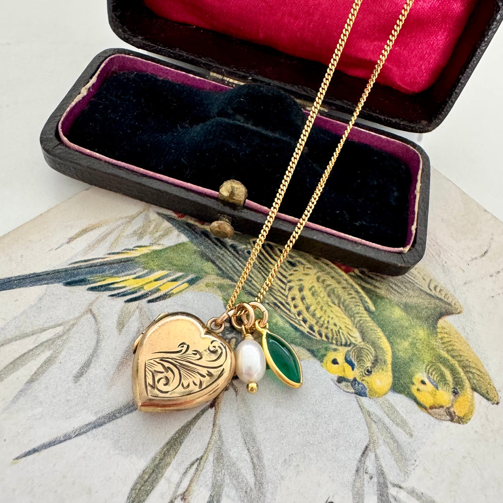 Vonk Jewellery rolled gold pearl and green onyx charm necklace on a vintage jewellery box and with a vintage postcard of love birds