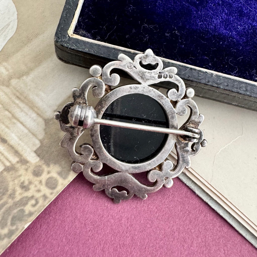 Back of Vonk Jewellery sterling silver and black onyx brooch with a vintage postcard and jewellery box